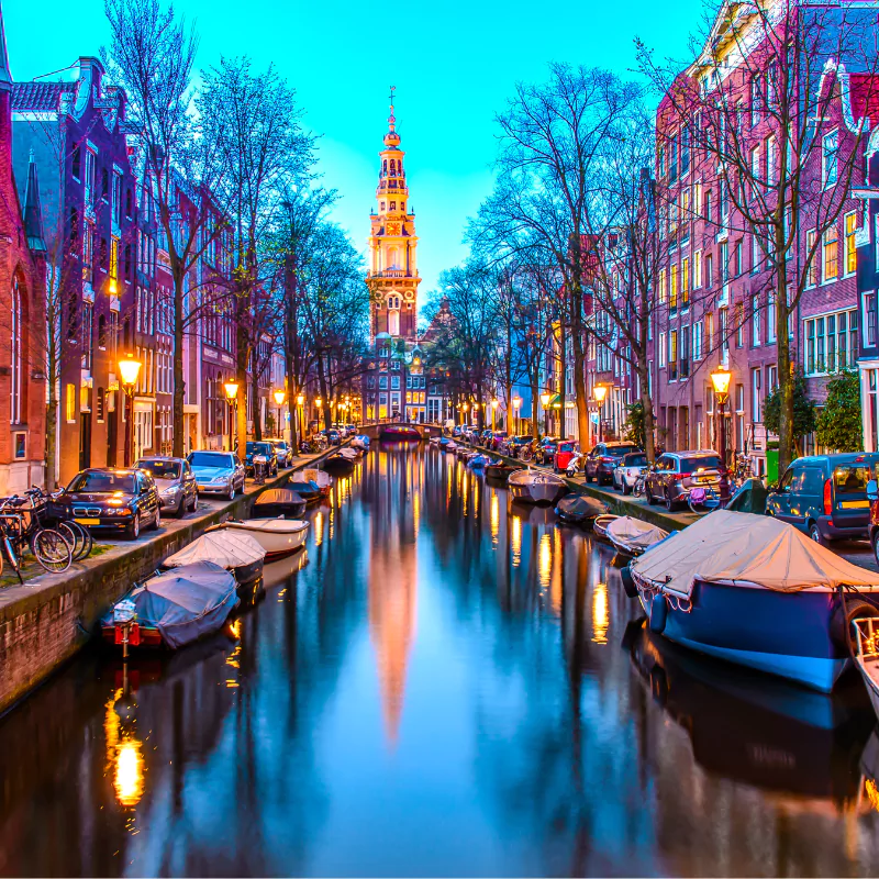 amsterdam canal with parked boats and cars